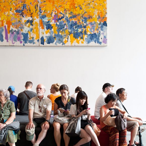Visitors seated below a large abstract artwork.