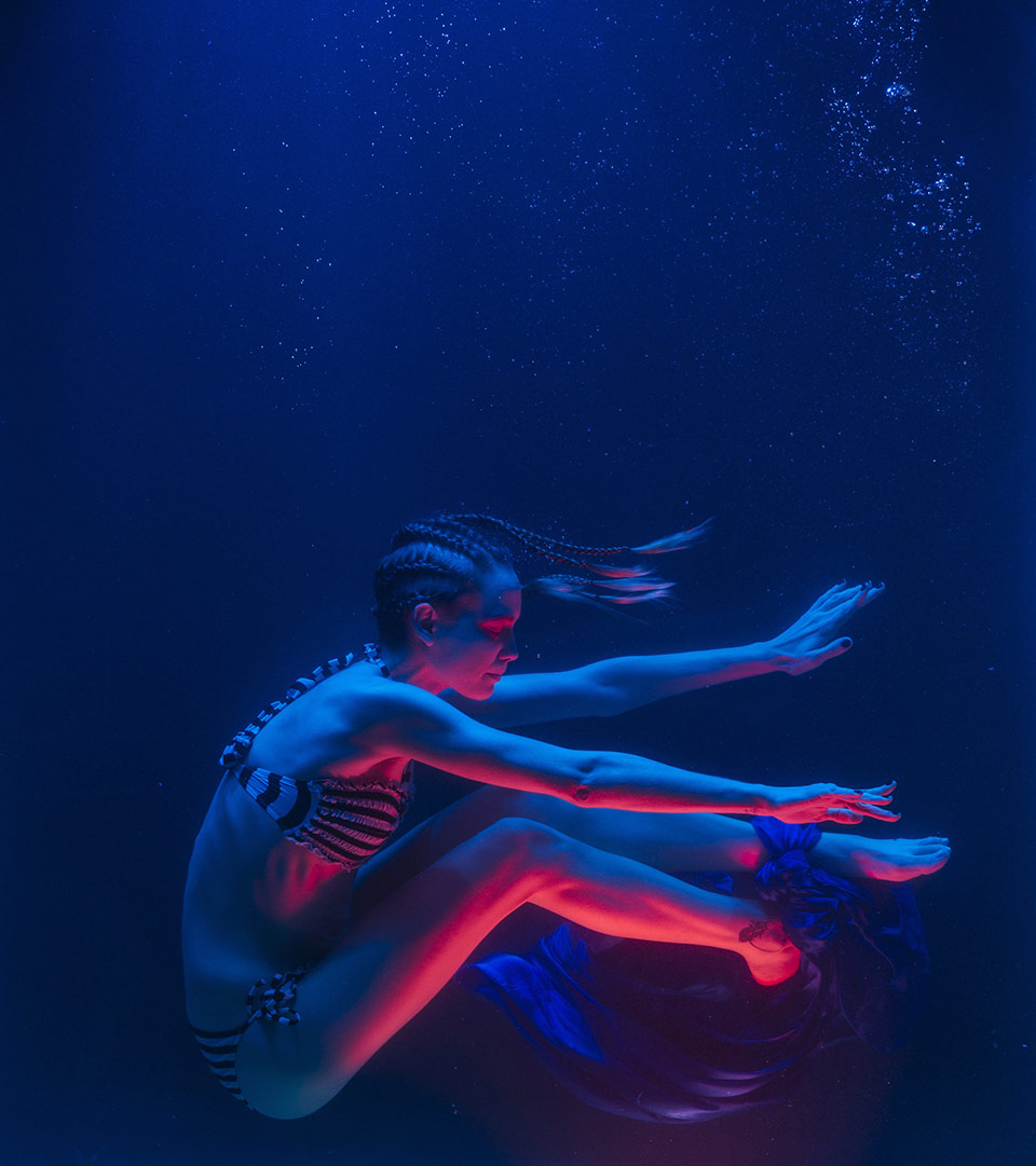 Performer in una sala espositiva illuminata di blu e rosso.